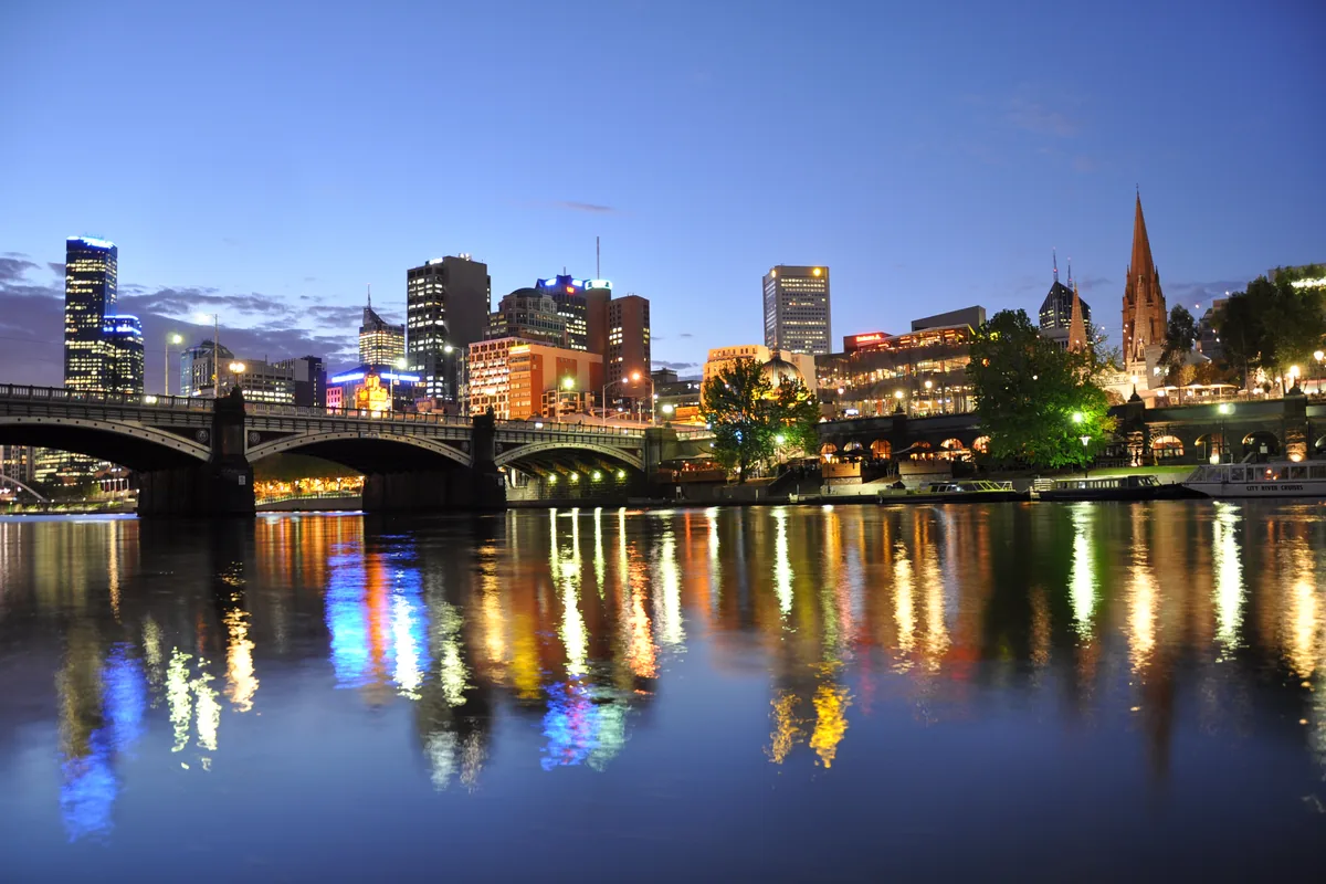 Princes Bridge, Flinders Street Station, Federation Square and the spires of St Paul's Cathedral along the Yarra at dusk, with lights reflected in the river