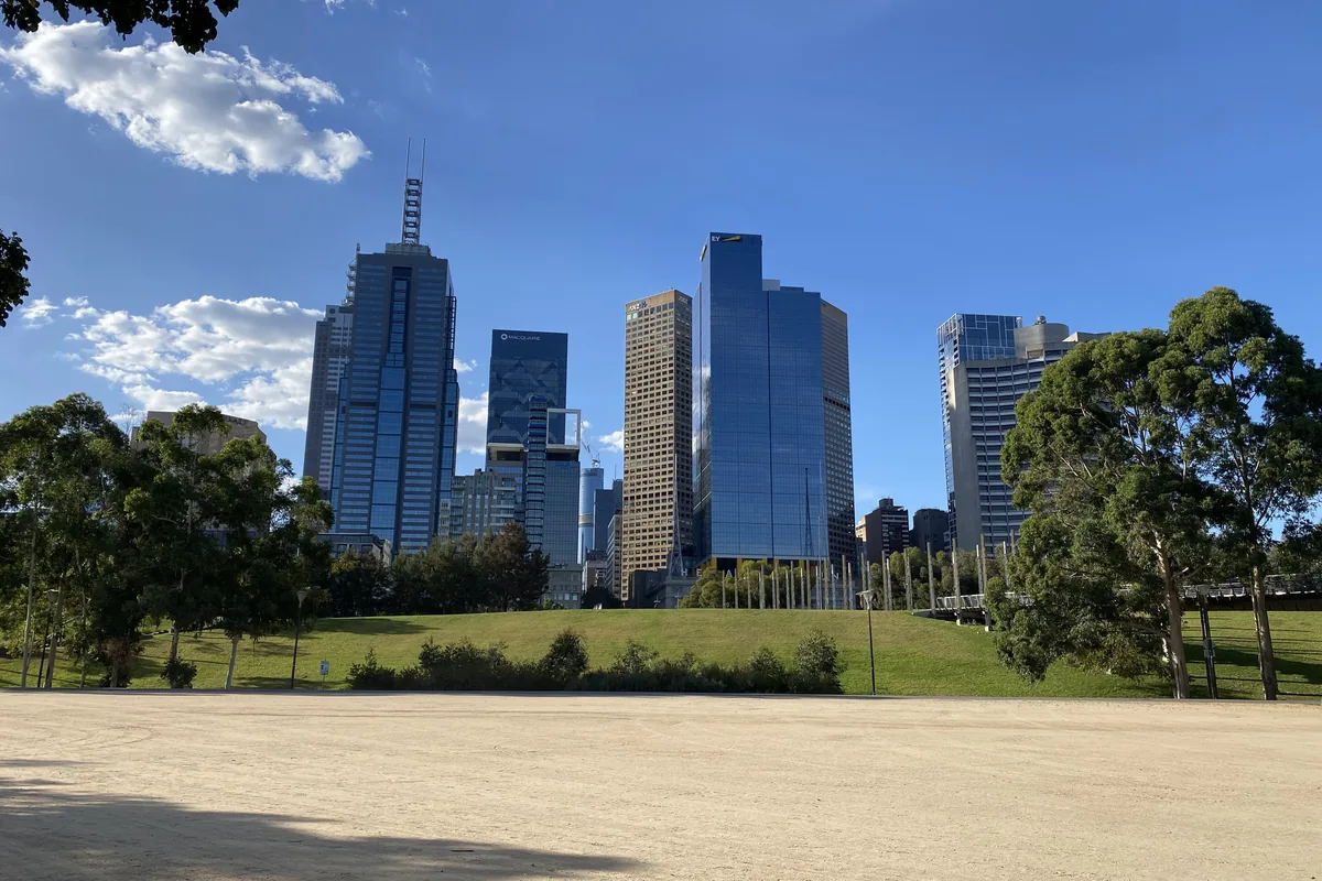 The lawn of Birrarung Marr with city towers rising behind a stand of gum trees.